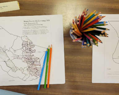 an overhead view of a paper map of Marin County on a table with dozens of colored pencils