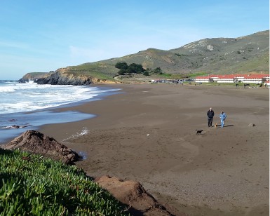 A man and woman walk their dog on Rodeo Beach in the Marin Headlands.