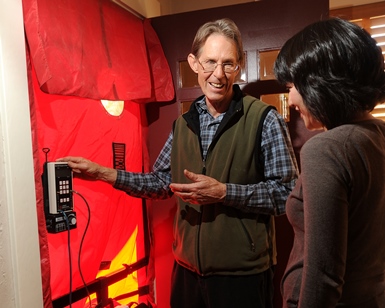 A man from the BayREN home energy program points to a thermostat as he talks with a female homeowner.