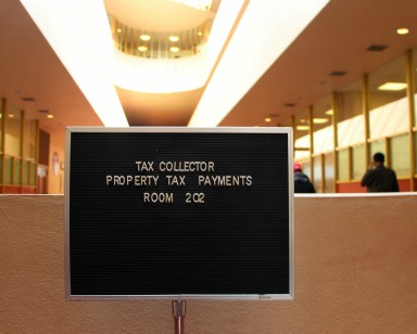 A sign in the Civic Center lobby shows that property taxes can be dropped off in Suite 202.