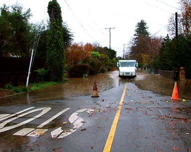 A mail delivery truck navigates a flooded roadway in Novato.