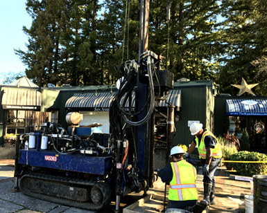 Two men operate a drilling machine outside of a property that straddles San Anselmo Creek.