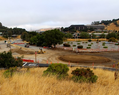 A hilltop view looking down on the Civic Center Drive traffic roundabout under construction.