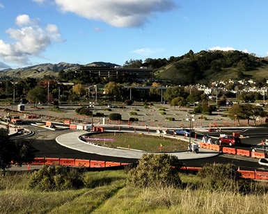 A view from a nearby hilltop shows the nearly completed roundabout intersection.