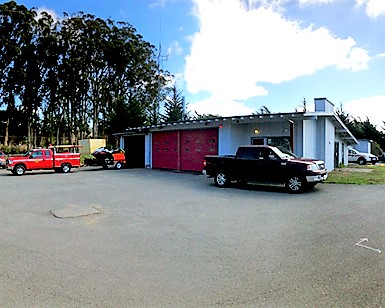 An exterior view of the Tomales Fire Station with several trucks out front.