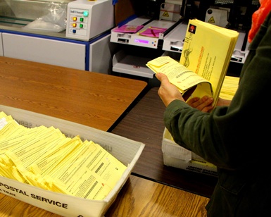 An election worker thumbs through mailed ballots on Election Day at the Civic Center.