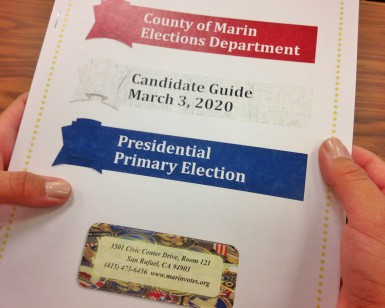 A closeup view of a person's hands holding a candidate guidebook for the March 2020 election.