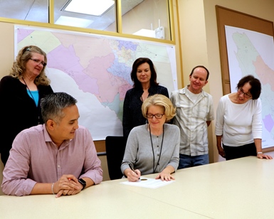 Registrar Lynda Roberts signs the document that completes the November 8 General Election as members of her staff look on.