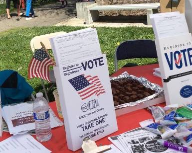 A tabletop display of pamphlets promoting voter registration.