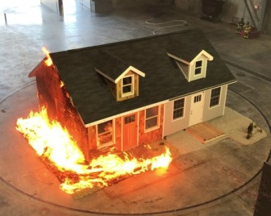 A tabletop model of a typical single-family home shows how fire resistant materials don't burn and traditional materials burn.