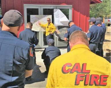 Fire Incident Commander Mark Brown provides a briefing to a group of firefighters.