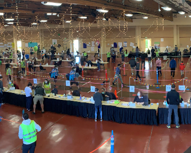 An interior view of the vaccination operation inside Exhibit Hall on the Marin Center campus showing dozens of people spread out in the large room.