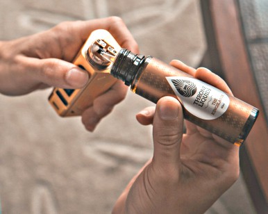 Two hands are shown with a vaping product.