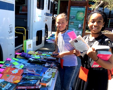 Two pre-teen girls pick out books at the Bookmobile.
