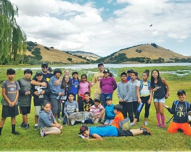 About a dozen elementary school and middle school kids on a lawn at Stafford Lake Park in Novato.