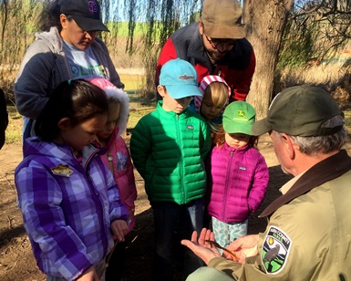 Parks naturalist David Herlocker talks to young kids about a feather he's holding in his hands.