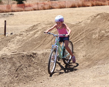 A girl of about 7 years old rides her bike on a dirt course at the Stafford Lake Bike Park near Novato.