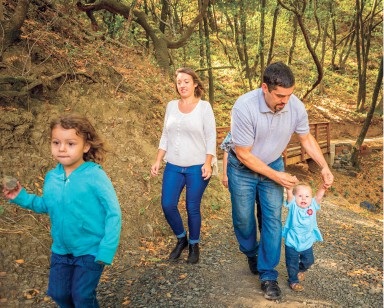 A husband and wife walk on a trail with their two young kids.