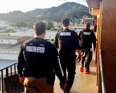 Three Probation officers walk on an apartment balcony during a DUI compliance check.
