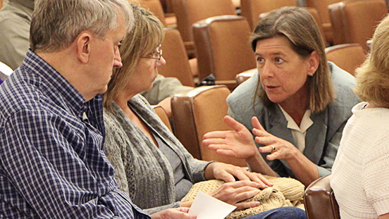 Supervisor Katie Rice speaking with 2 people at a Board Of Supervisors meeting.