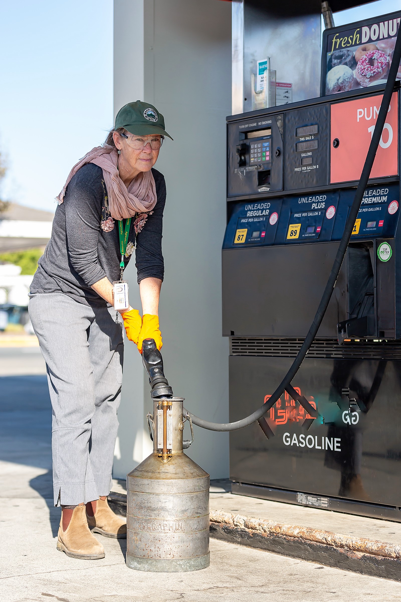 A female inspector fills a gasoline container with a gallon of gas at a service station.
