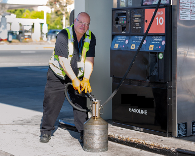A male weights & measures inspector pumps gasoline into a container to check accuracy.