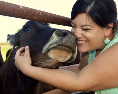 A woman smiles as she hugs a cow's head at a Marin dairy.