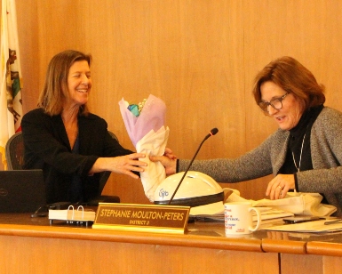 Supervisor Katie Rice, left, accepts a bouquet of flowers from Supervisor Stephanie Moulton-Peters, right.