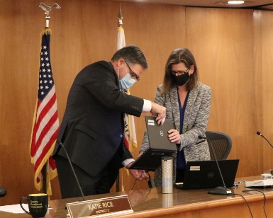 Supervisor Dennis Rodoni, left, passes a laptop computer to Supervisor Katie Rice, right, as they change seating positions on the dais during the Board of Supervisors meeting on January 4, 2022. 
