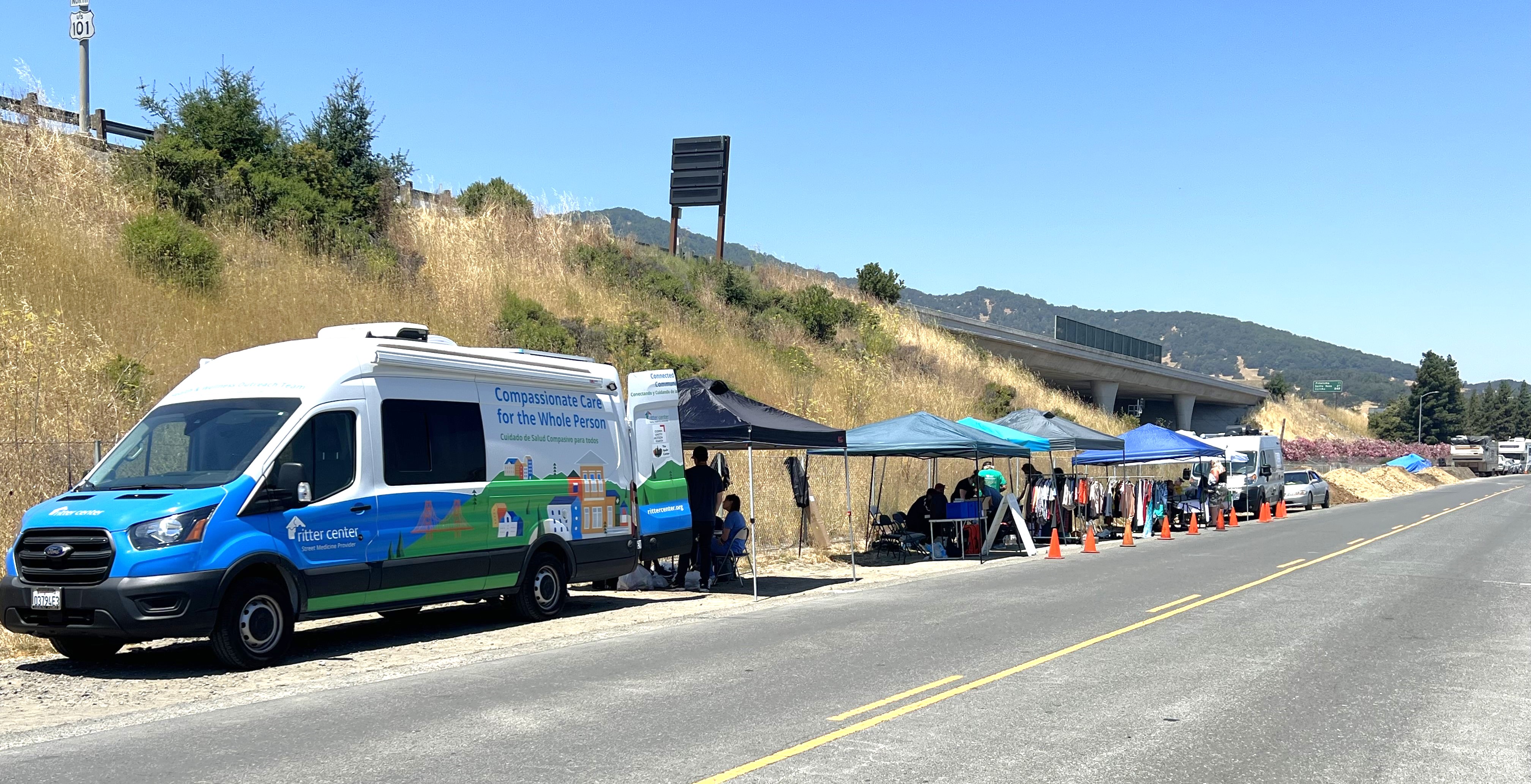 A view of Binford Road shows a van with supportive services open to assist residents as well as tents set up with resources.