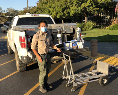 A male Marin County Parks employee unloads a pickup truck during a delivery.