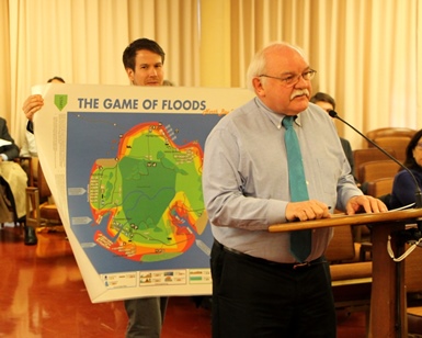 Jack Liebster speaks to the Board of Supervisors about the 'Game of Floods' as cohort Alex Westhoff holds up the game.