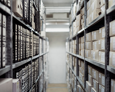 Long aileway of bookshelves, full of books and files. 