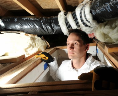 An installer inspects home insulation