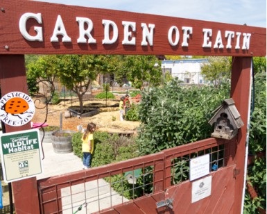 The entrance to a community garden, with a sign reading Garden of Eatin'.