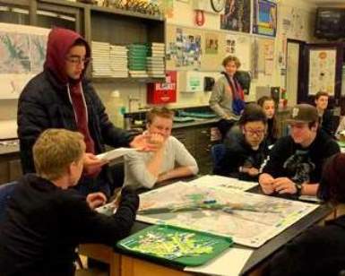 Students at Tamalpais High sit around a table and look at a map showing future sea-leve rise patterns.