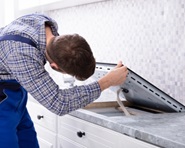 A kitchen appliance maintenance man works on installation of an electric stove.