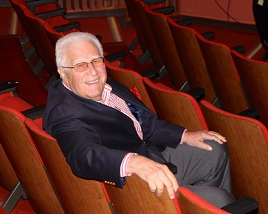 Lido Cantarutti sits in a chair and smiles at the Showcase Theater.