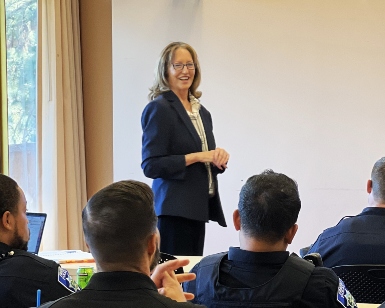 District Attorney Lori Frugoli smiles as she looks out into a classroom of seated participants.