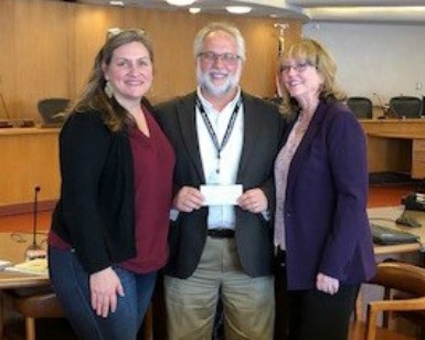 Three people pose with a donated check.