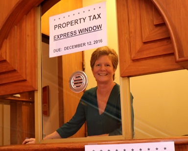 Sandra Kacharos smiles from an information booth at the Civic Center that will serve as a property tax dropoff point.