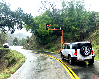 A vehicle is shown stopped in front of a temporary traffic signal on rural Bolinas Road.