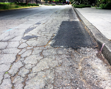 A closeup view of patchy and cracked pavement that is scheduled to be repaved in the Sleepy Hollow neighborhood.