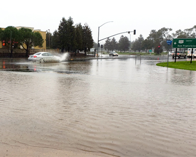 A car splashes through a giant puddle on Donahue Street in Marin City