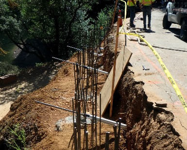Vertical pilings are shown being installed next to Fairfax-Bolinas Road near Fairfax.