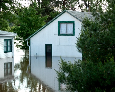 A flooded house is reflected in flood waters