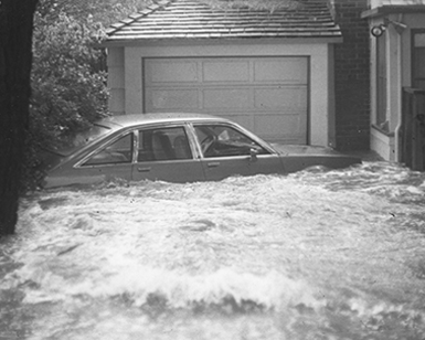 A car is shown on a Belvedere driveway nearly up to its windows in floodwater.