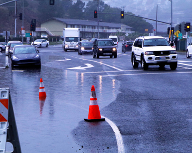 Photo of a large puddle taking up a portion of the road near the Manzanita Park & Ride lot in Southern Marin, forcing vehicles to veer to one side of the road.