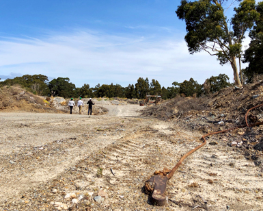 A ground-level view of the rock quarry in San Rafael with three people in hardhats seen in the distance.