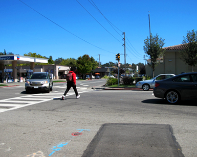 A pedestrian crosses Third Street in downtown San Rafael as cars await.